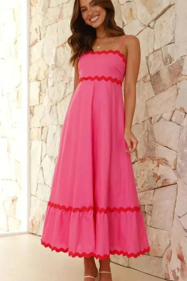 Model wearing the Kouvr Amillia pink scalloped maxi dress in front of a stone wall

