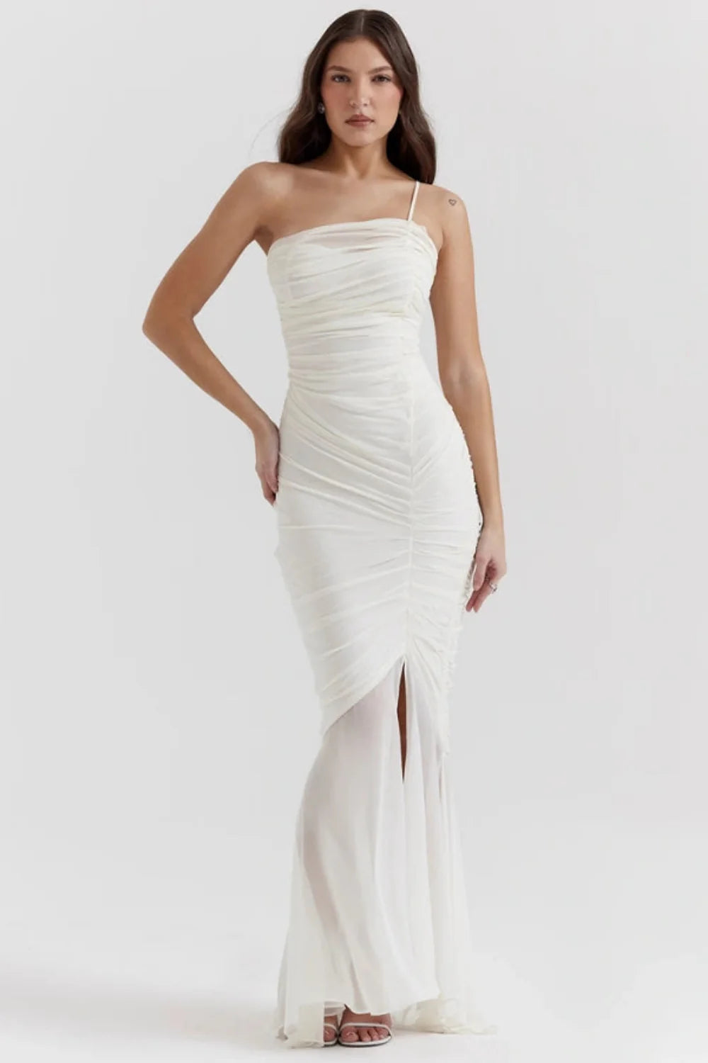 Model wearing the Kouvr Fashion Ruched white one-shoulder ruched maxi dress with a sheer mermaid hem and thigh-high slit