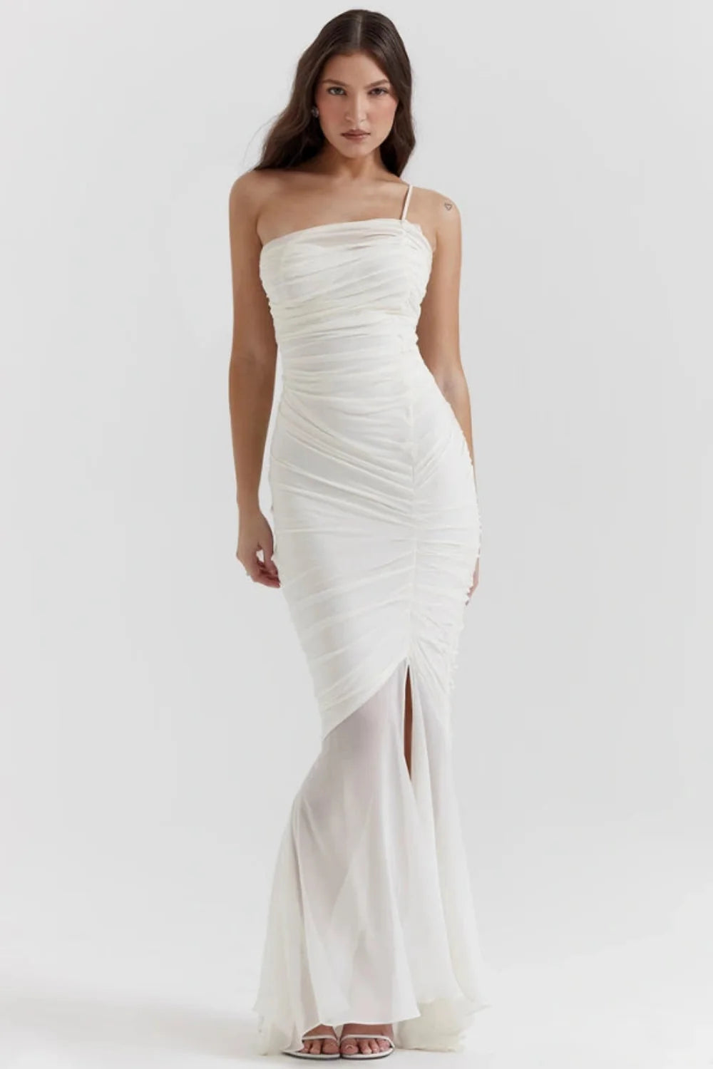 Model wearing the Kouvr Fashion Ruched white one-shoulder ruched maxi dress with a sheer mermaid hem and thigh-high slit