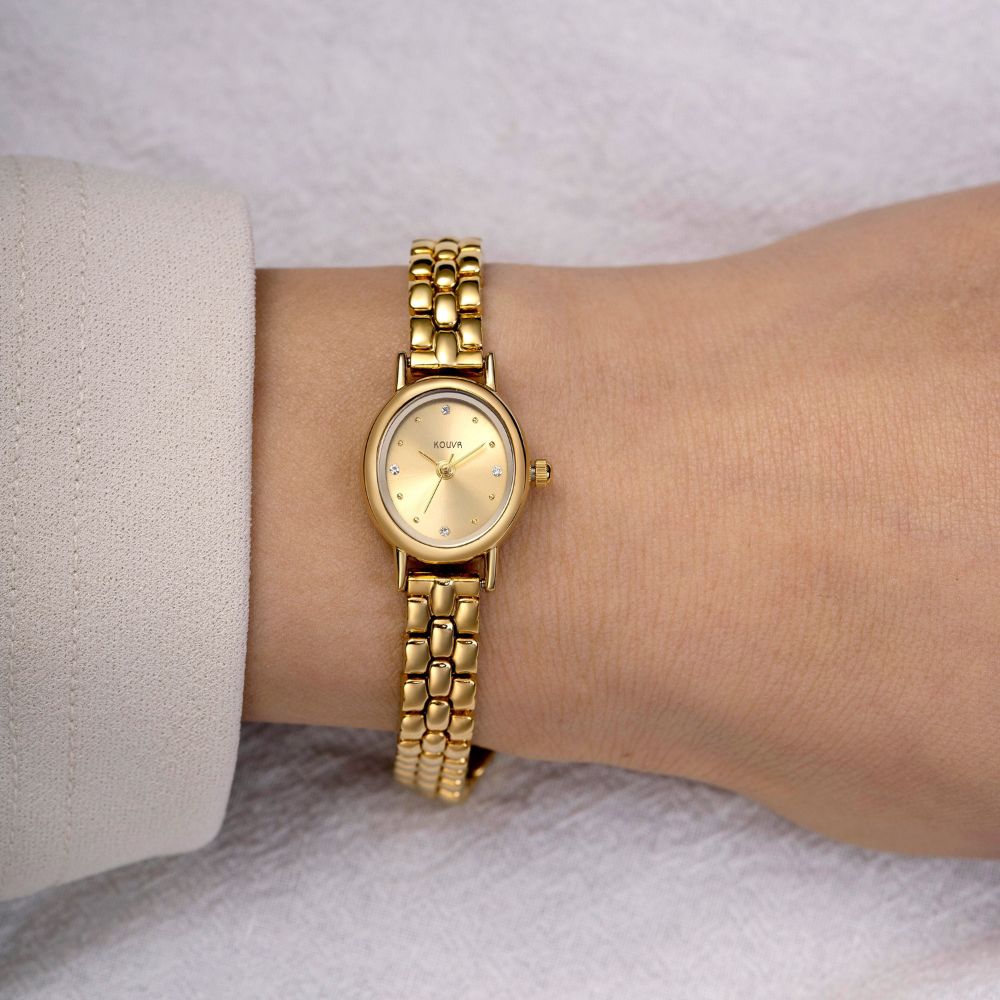 Gold kouvr wristwatch on a wrist with a neutral background