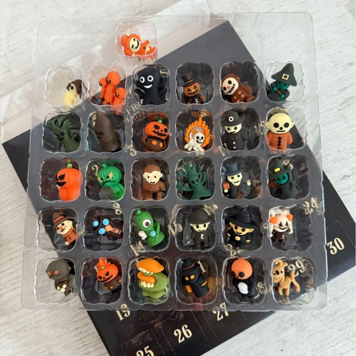 Close-up view of the 24 unique monster and spooky character toy figurines inside the plastic tray of the Halloween advent calendar.