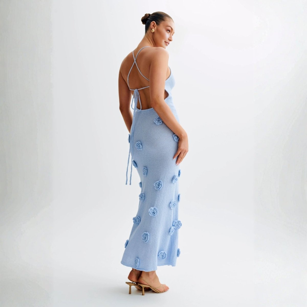 Woman wearing a light blue dress with floral embroidery on a white background