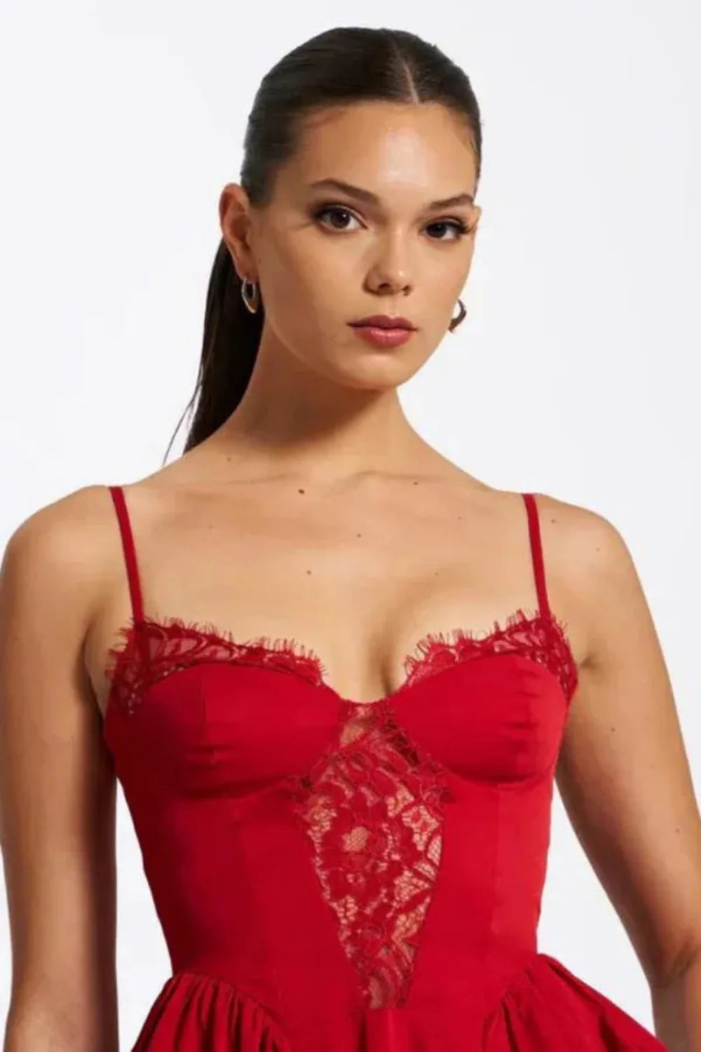 Model wearing Kouvr Amadi red corset midi dress with lace detail and hands in pockets