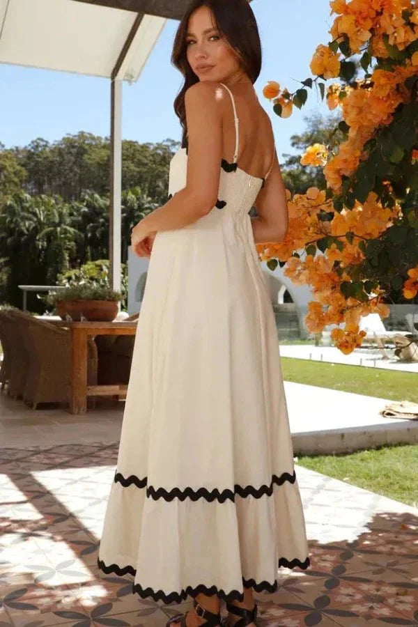 Woman wearing the Kouvr Fashion Amillia maxi dress with black scalloped trim on a sunlit patio