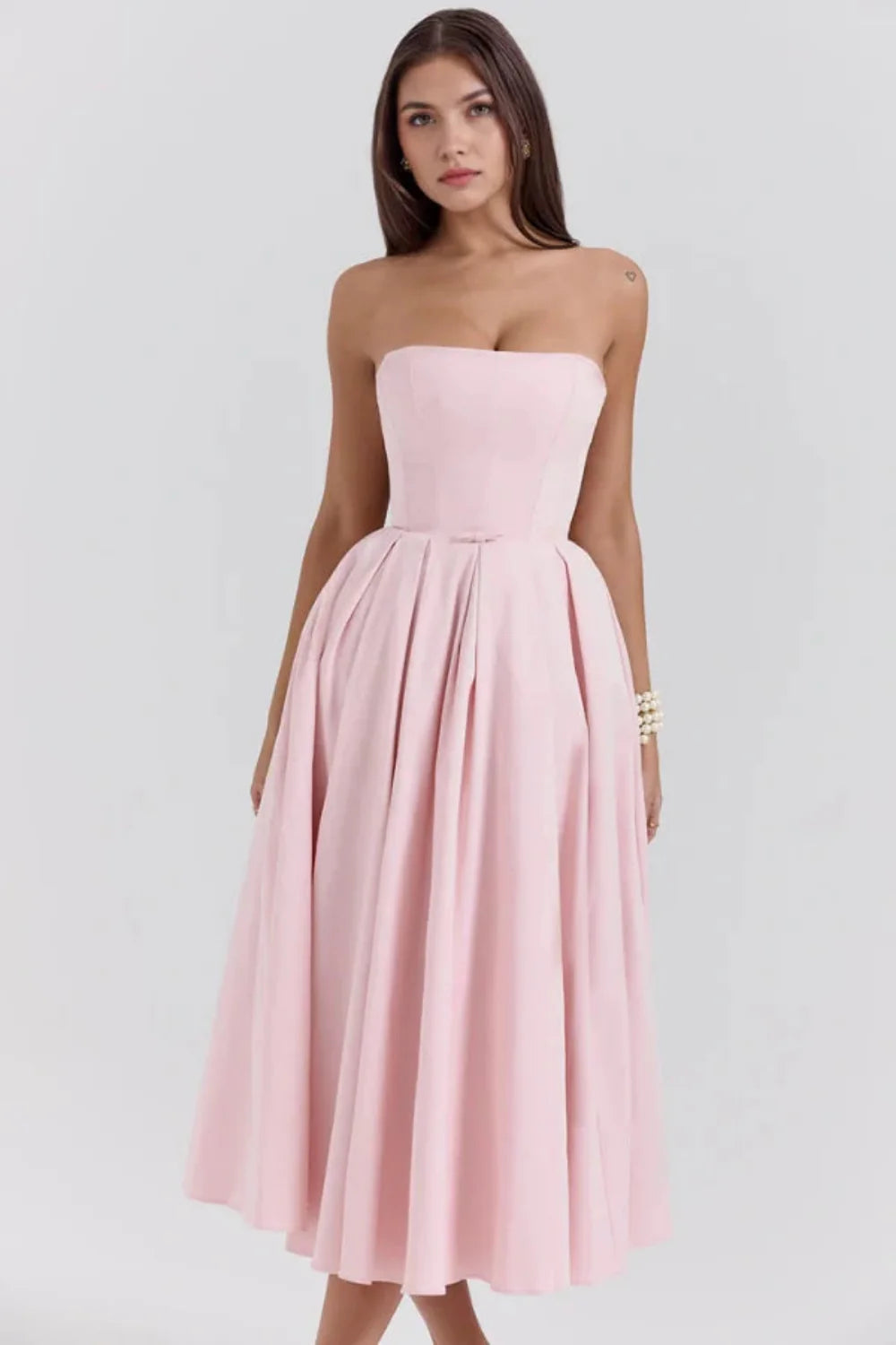 Model wearing the Kouvr Fashion blush pink strapless midi dress with a full pleated skirt