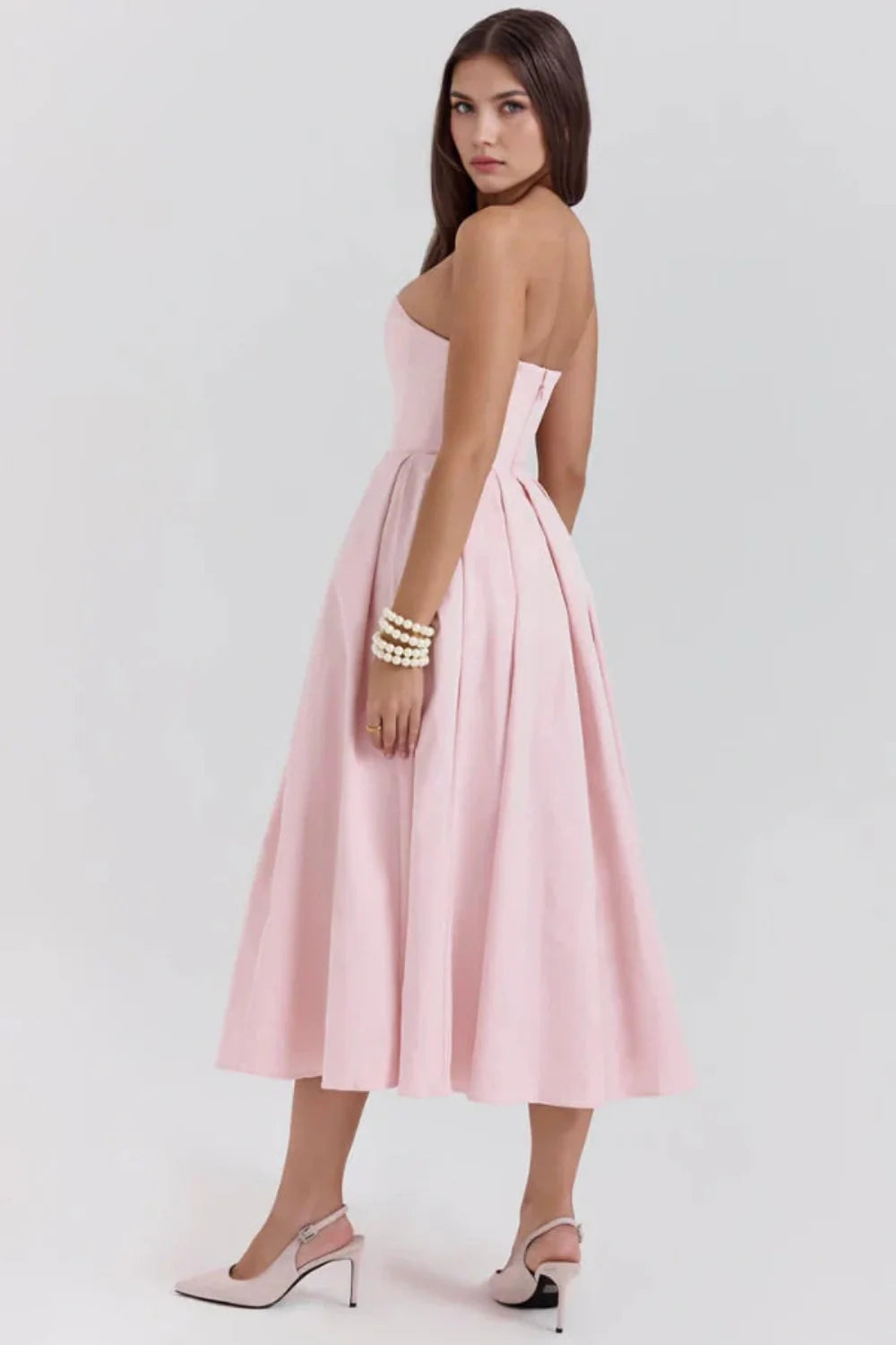 Model wearing the Kouvr Fashion blush pink strapless midi dress with a full pleated skirt