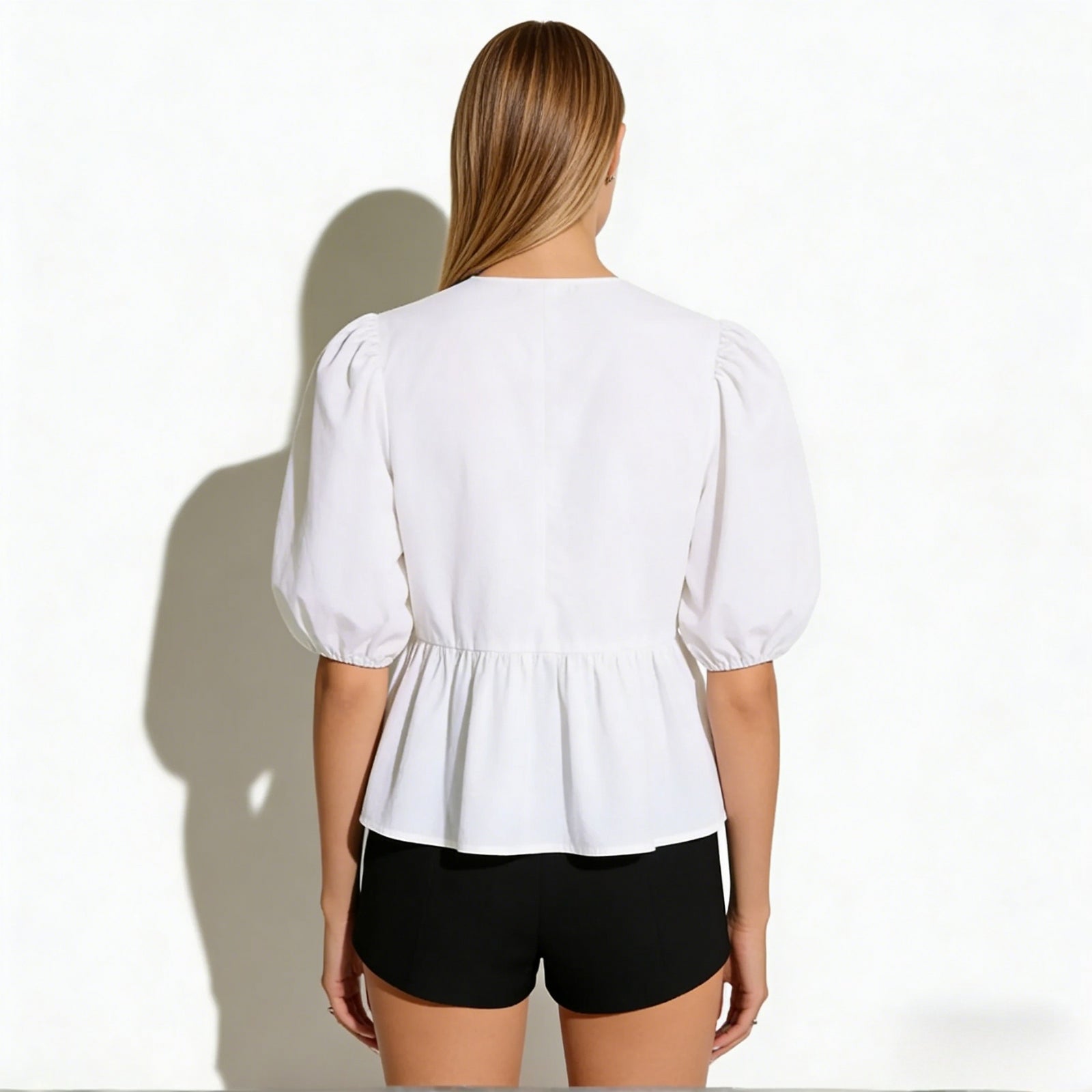 Back view of the Kouvr Anne blouse highlighting the clean lines, gathered waist, and puff sleeve construction. 