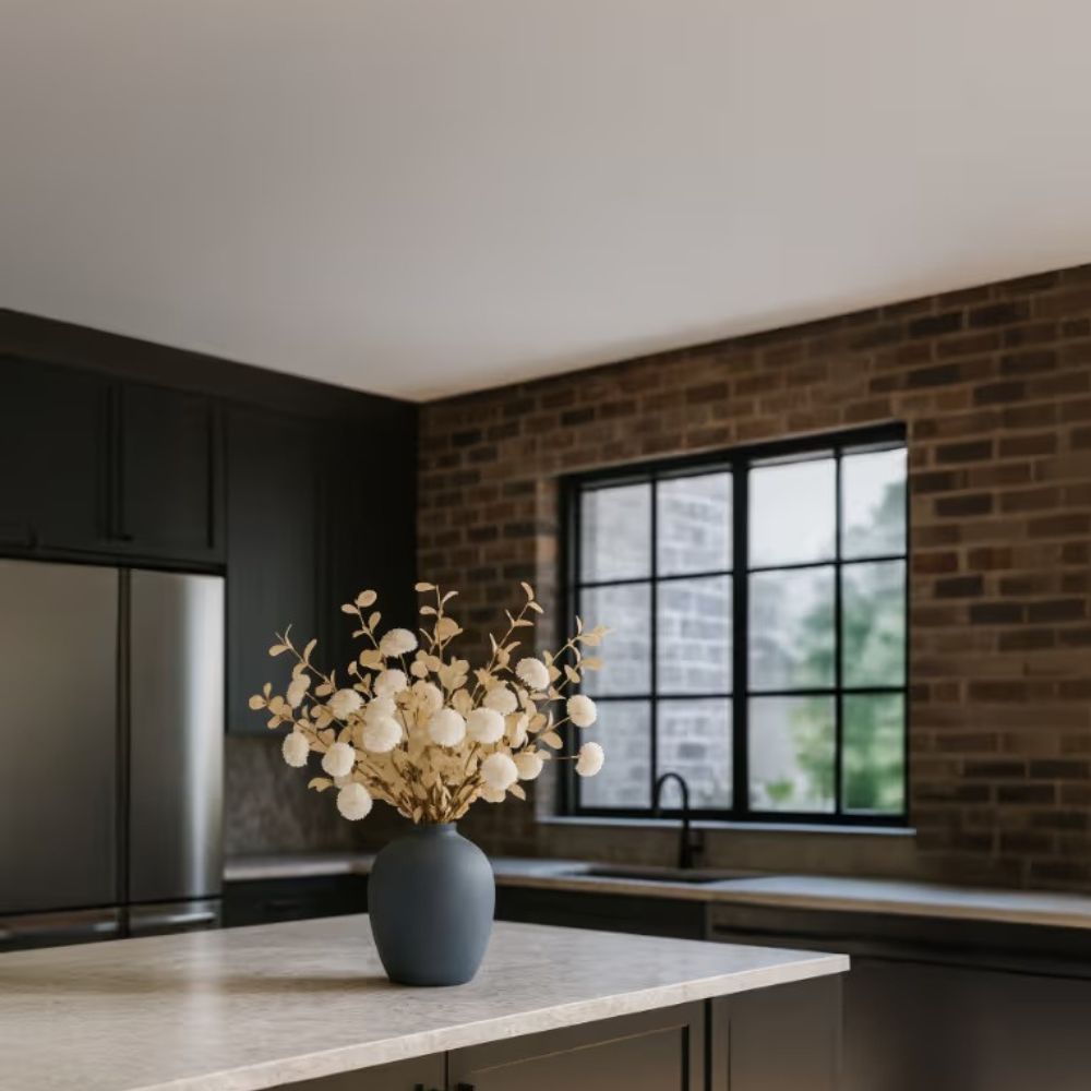 Kouvr Aspen Dream artificial flower arrangement with white pom poms and bleached eucalyptus in a modern matte black ceramic vase