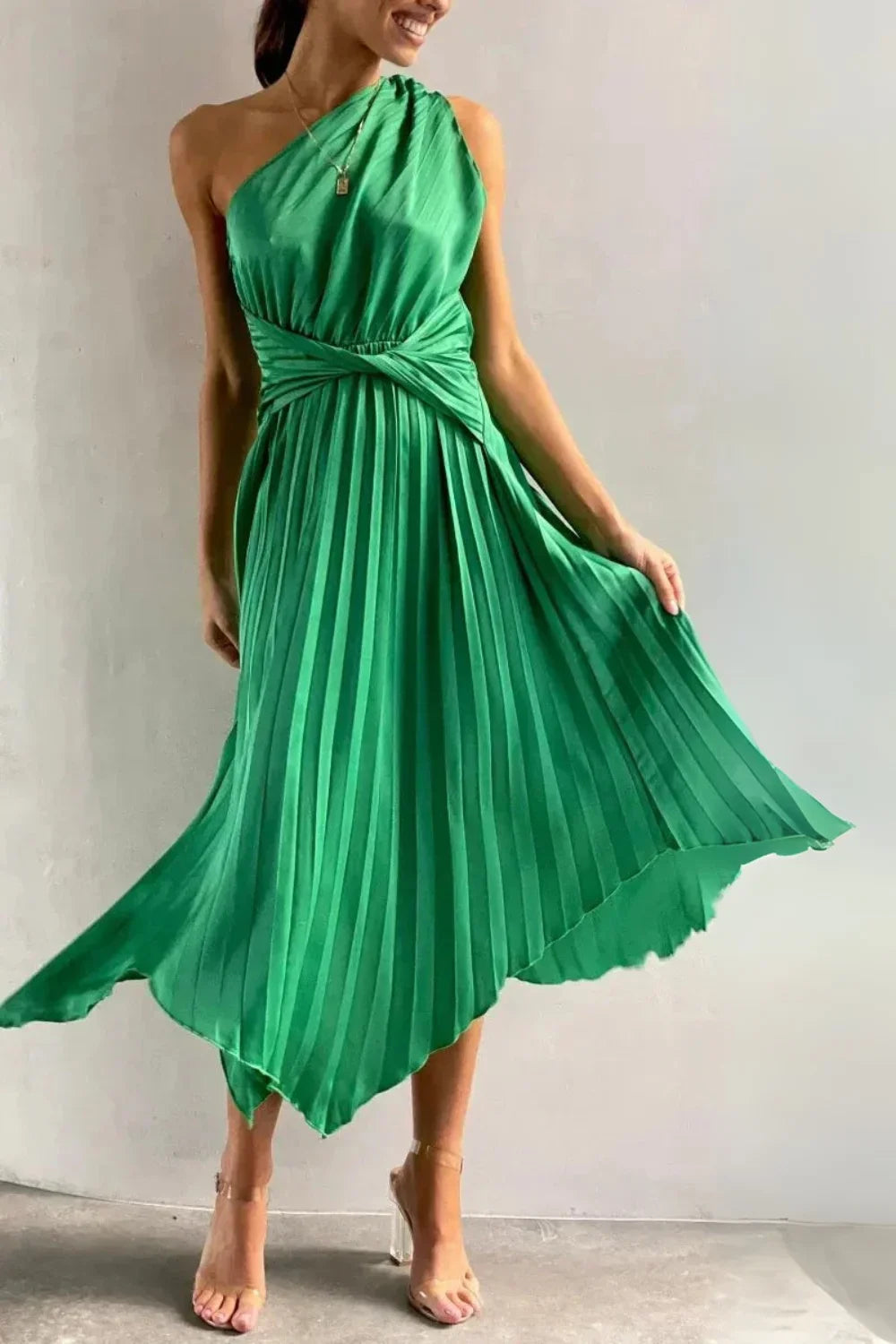 Model poses in the Kouvr Audrine green satin one-shoulder pleated midi dress for a formal event