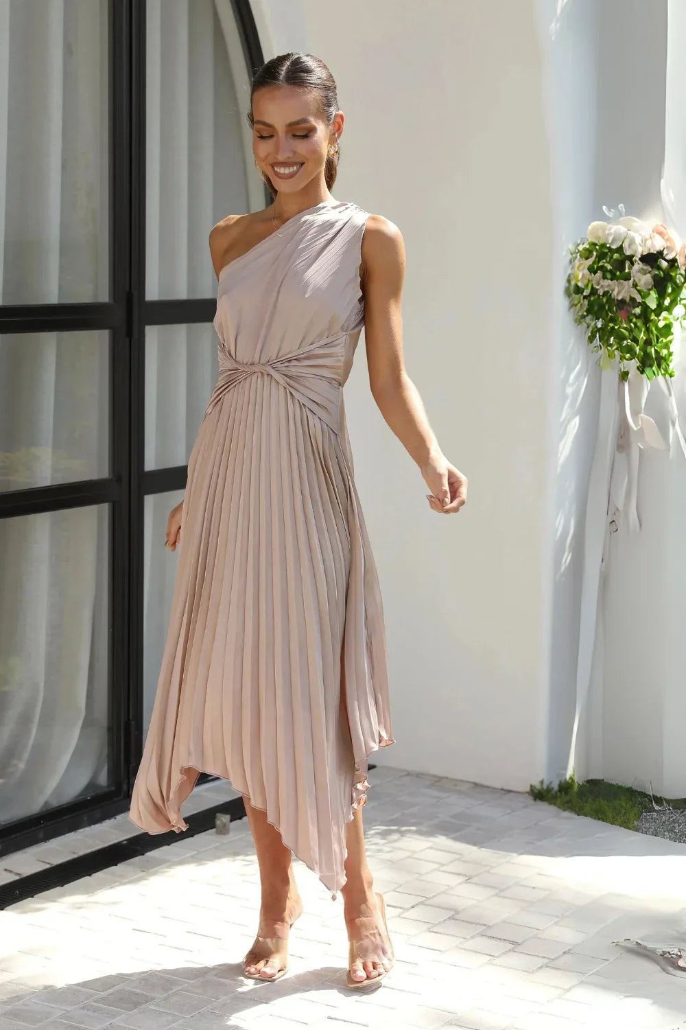 Model wearing Kouvr's beige one-shoulder pleated midi dress for a formal event