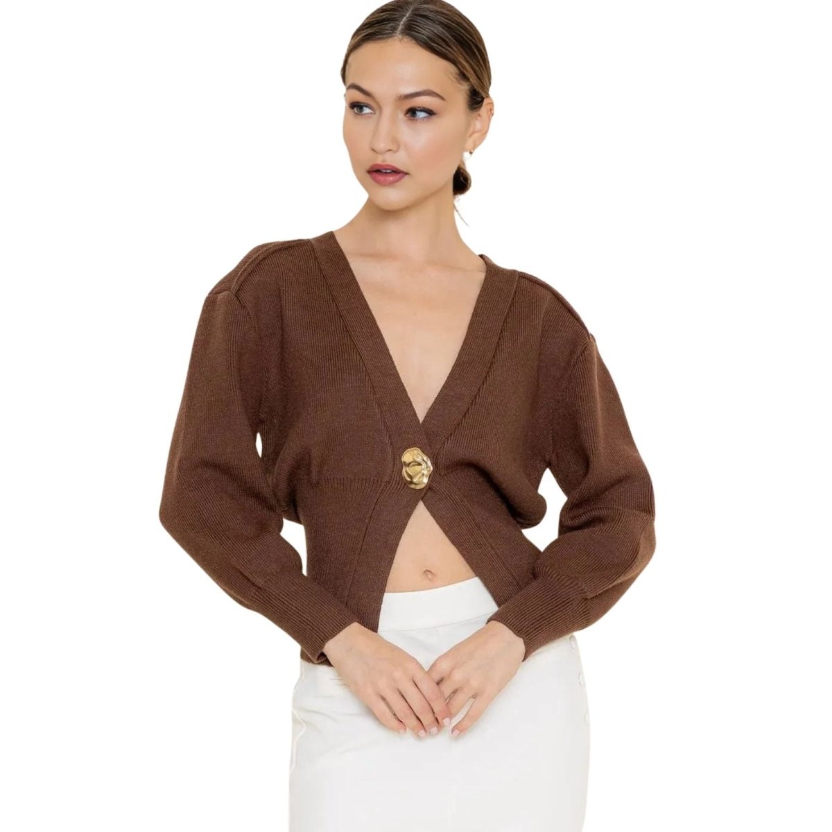 Woman wearing a brown kouvr cropped cardigan with a gold emblem on a white background