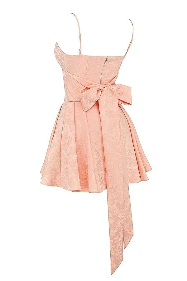 Model wearing Kouvr Ayliah peach jacquard mini dress with large bow detail at the back