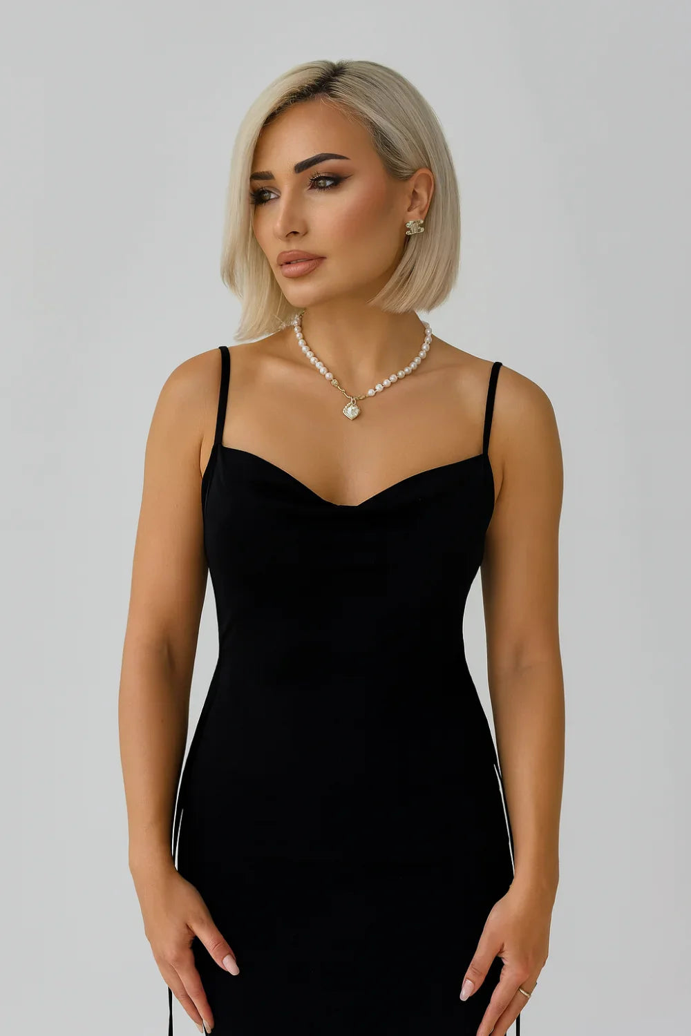 Woman wearing Kouvr black backless silk slip dress with pearl necklace" and "Detailed view of the low open back and adjustable straps on the Kouvr evening dress