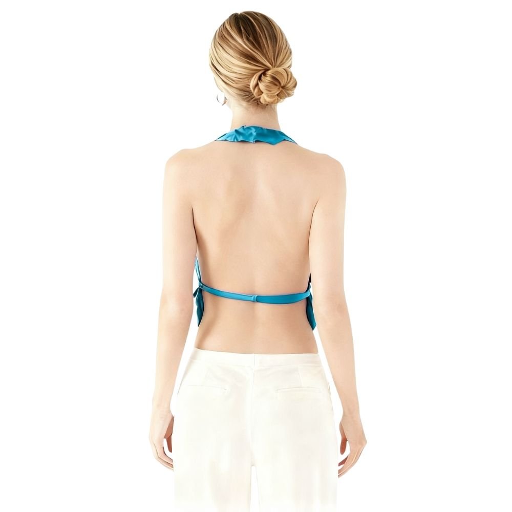 Woman wearing a blue kouvr bikini top with a white skirt on a white background