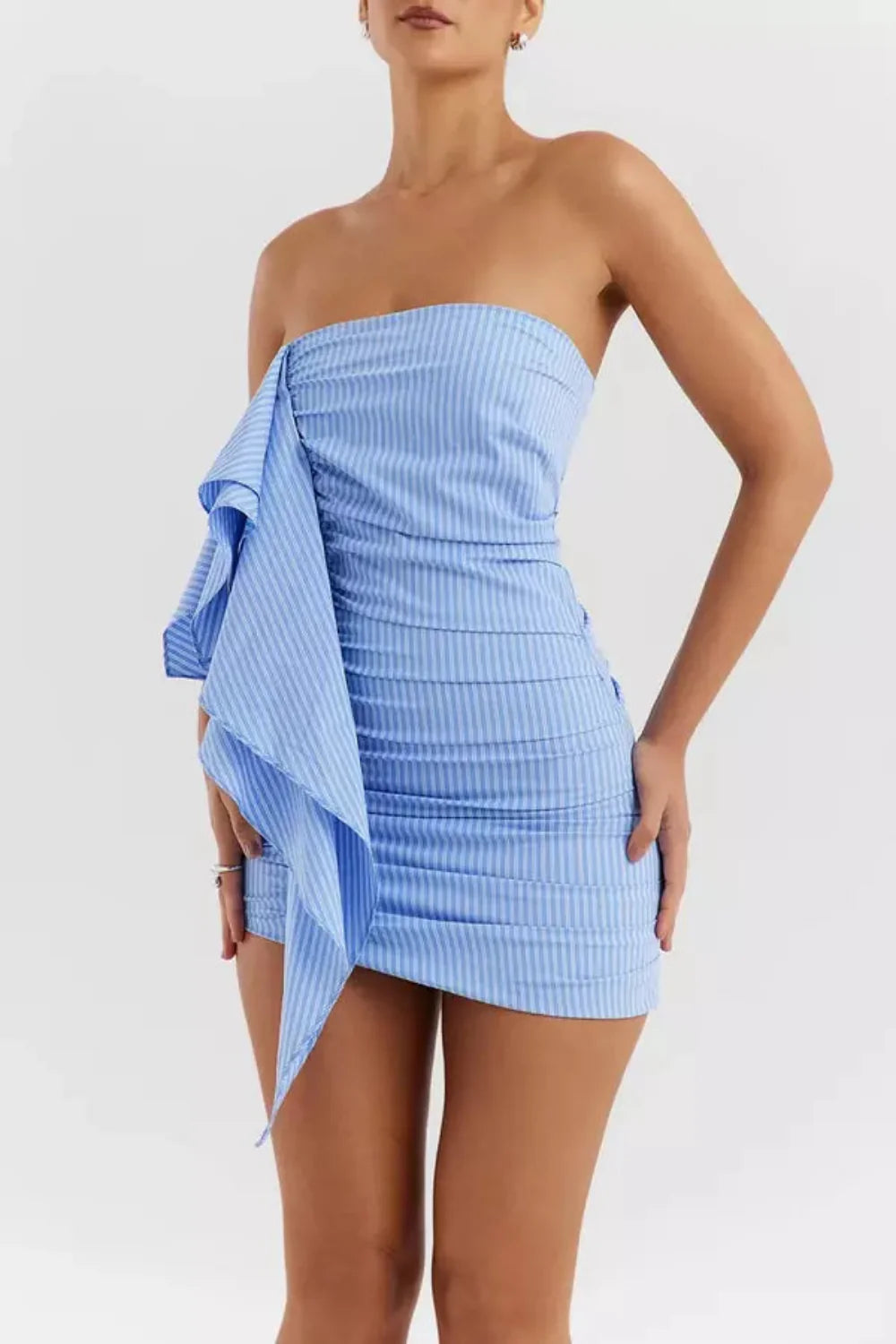 Model wearing Kouvr's blue and white striped strapless mini dress with a large asymmetrical side ruffle
