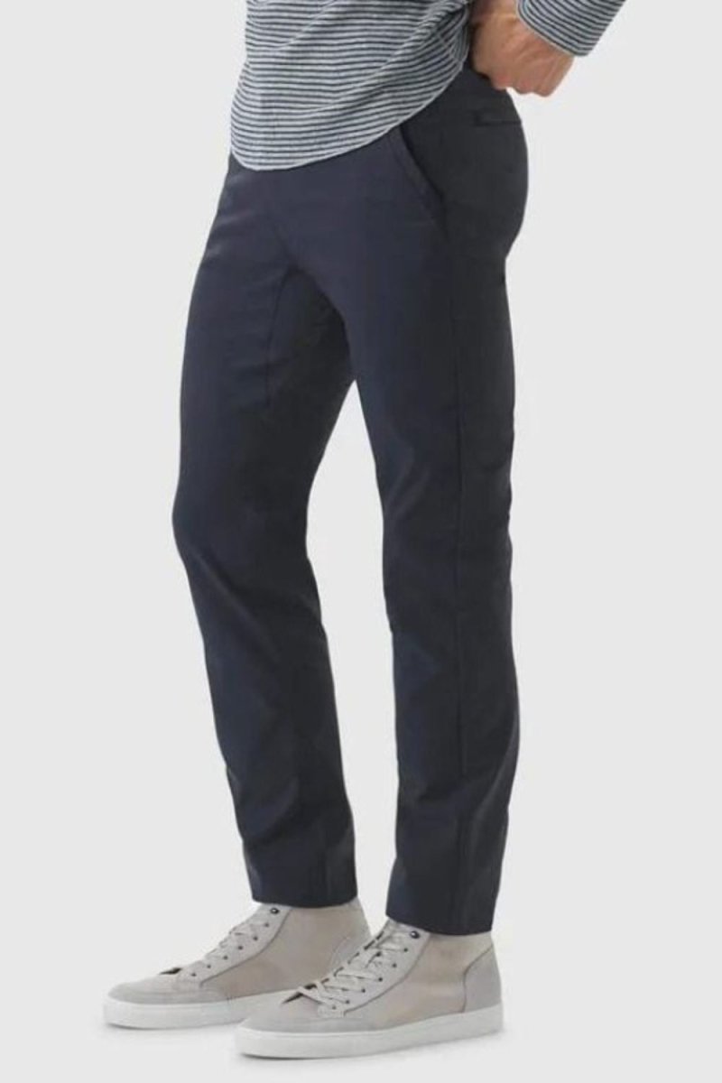 Model wearing the Kouvr Dark Blue Pant in navy with a light blue dress shirt and white leather sneakers