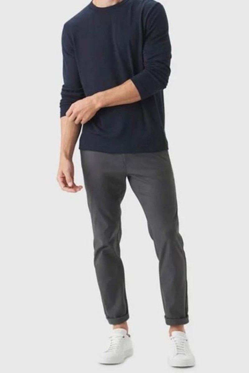 Man wearing Kouvr Calvin black slim fit technical trousers with a navy long-sleeve shirt and white sneakers