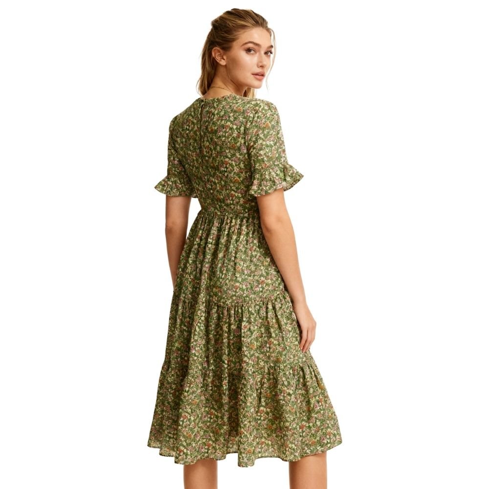 Woman wearing a green kouvr floral dress on a white background