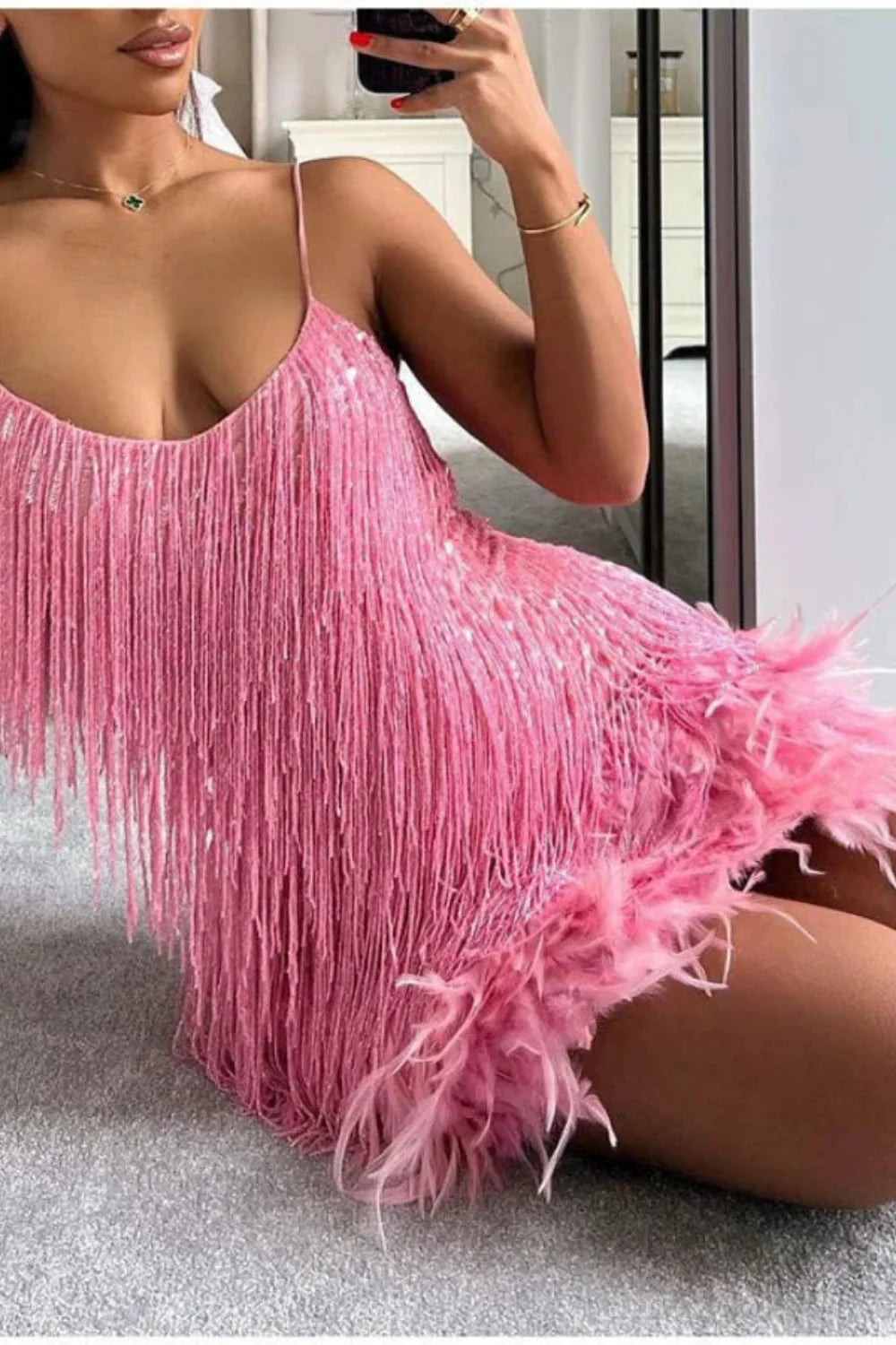 Model wearing Kouvr Elena pink feather fringe mini dress with sequin detail, holding a white bag
