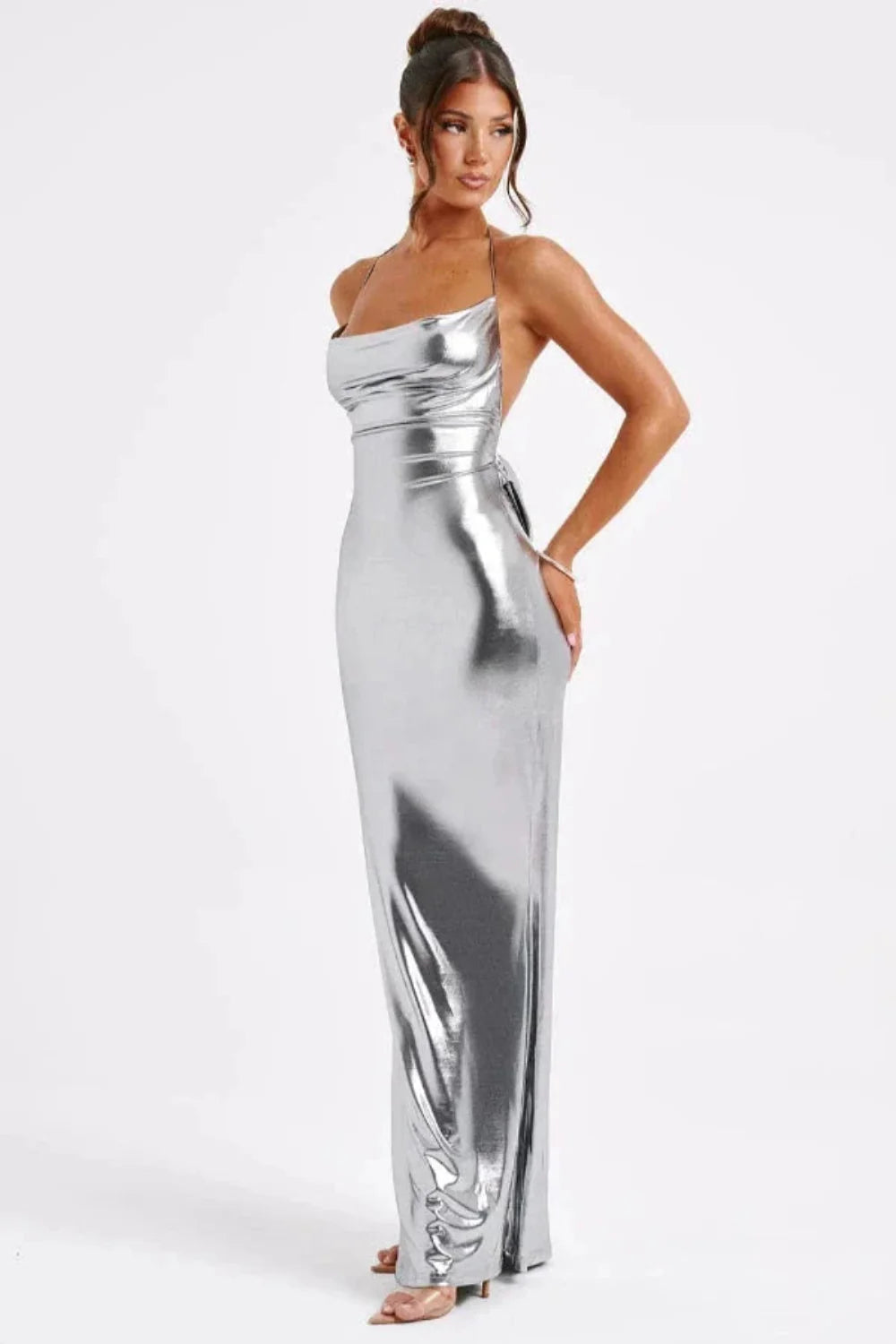 Model wearing Kouvr Elysian silver metallic backless halter gown showing side profile
