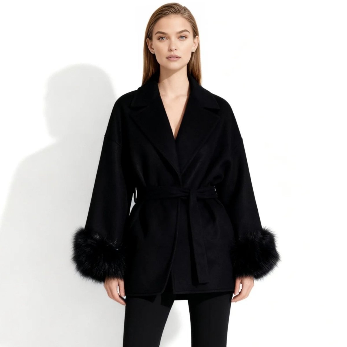 Model wearing the Kouvr Emma black wool belted jacket with statement fox fur cuffs, viewed from the front against a white background.