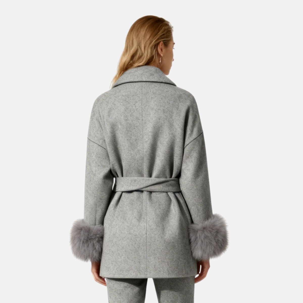 Woman wearing a gray coat with fur cuffs on a white background