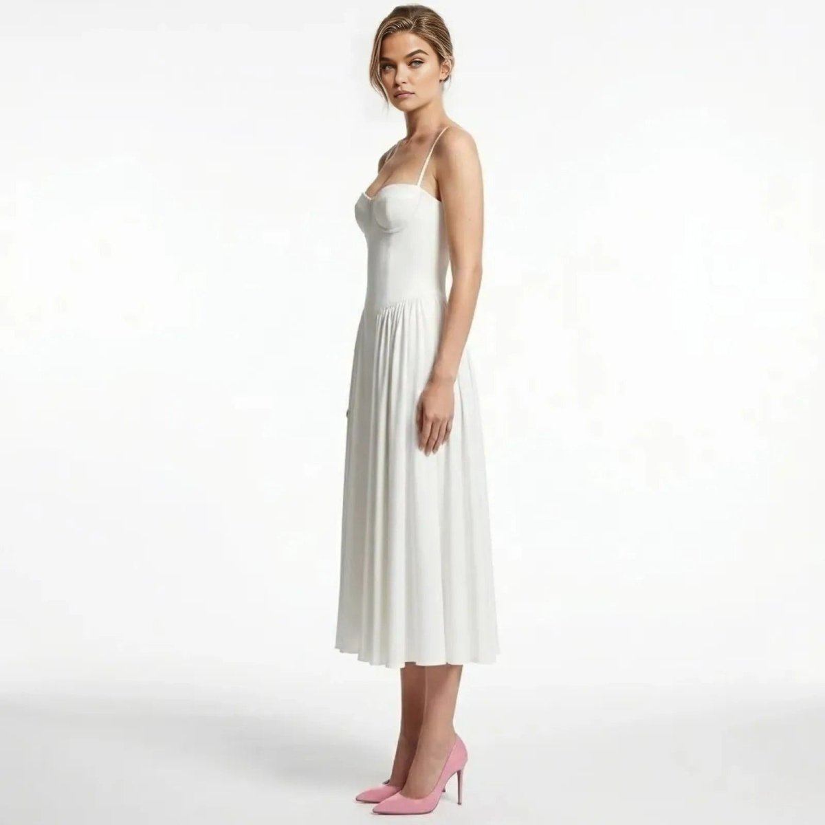 Side profile of a model in the Kouvr Fashion Evdokia white midi dress showing the structured bodice and pleated A-line skirt.