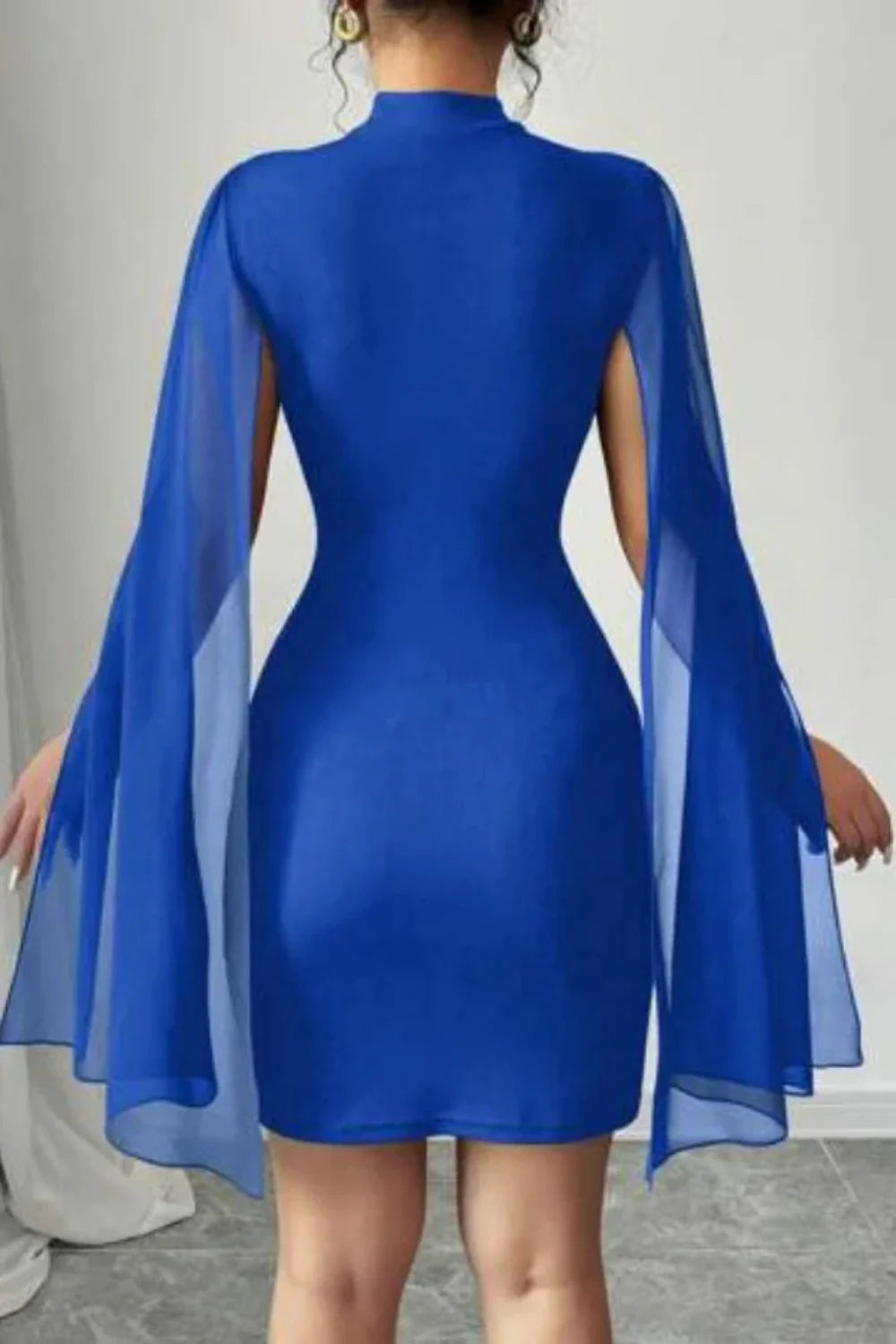 Woman wearing Kouvr Fashion's Eya blue mock neck bodycon dress with sheer cape sleeves