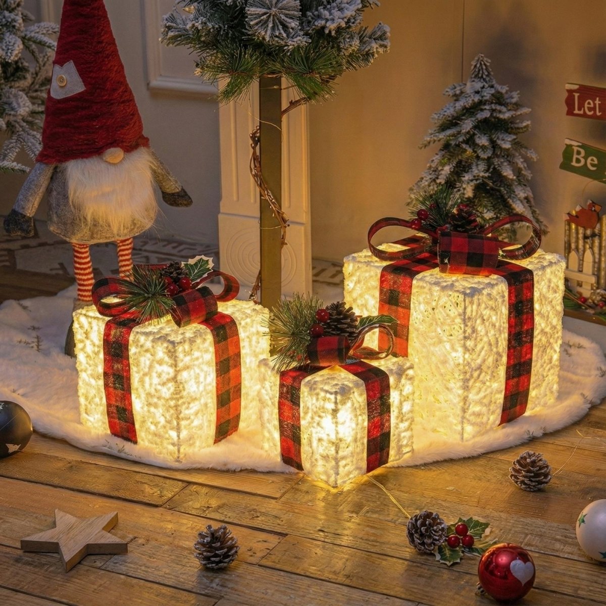 Lifestyle view of three glowing gift boxes as a centerpiece for farmhouse Christmas decor, next to a Nordic gnome and miniature pine trees.