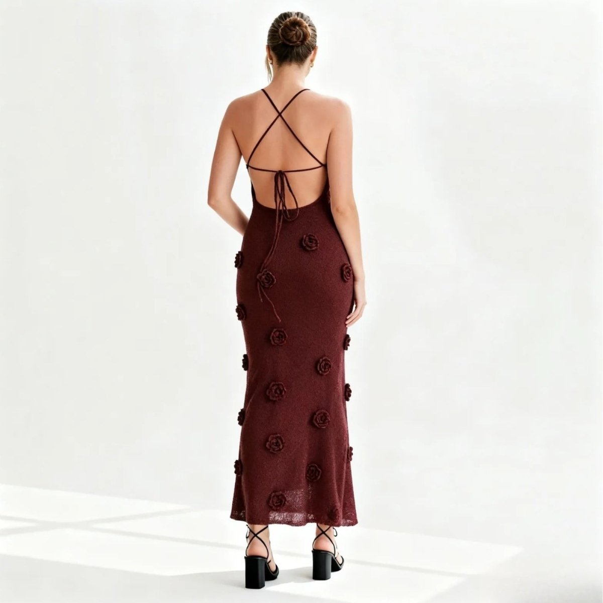 Woman wearing a burgundy kouvr dress with floral embellishments on a white background