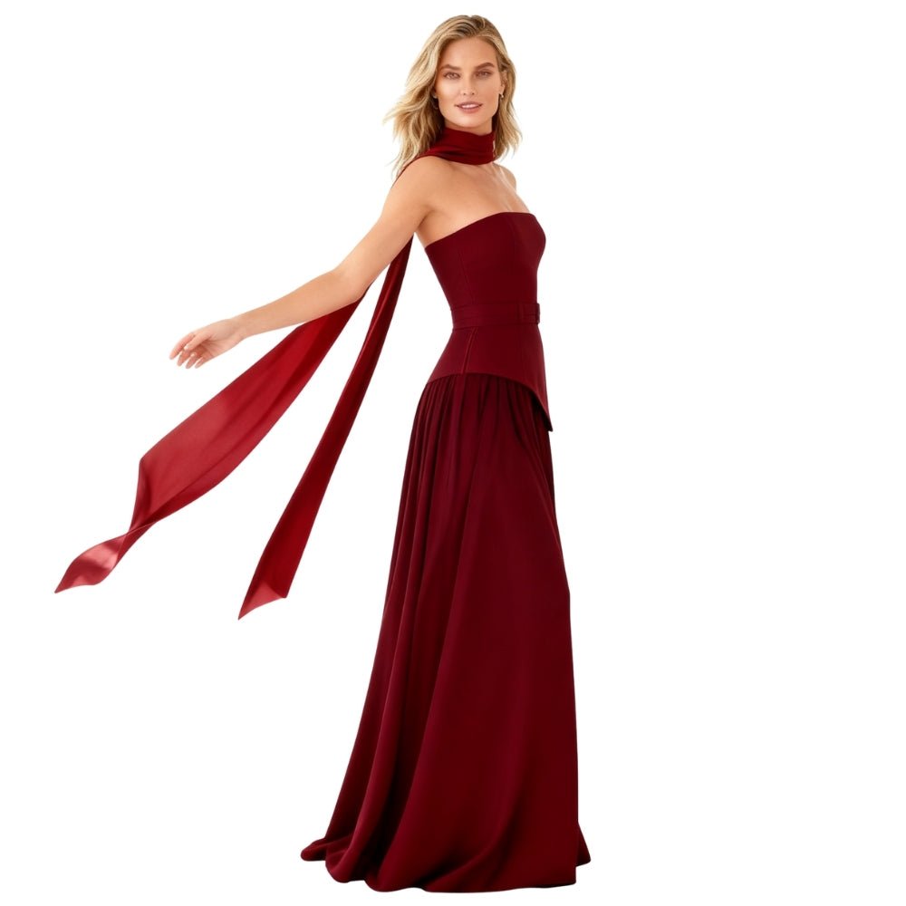 Woman wearing a burgundy Kouvr one-shoulder gown with a flowing fabric on a white background