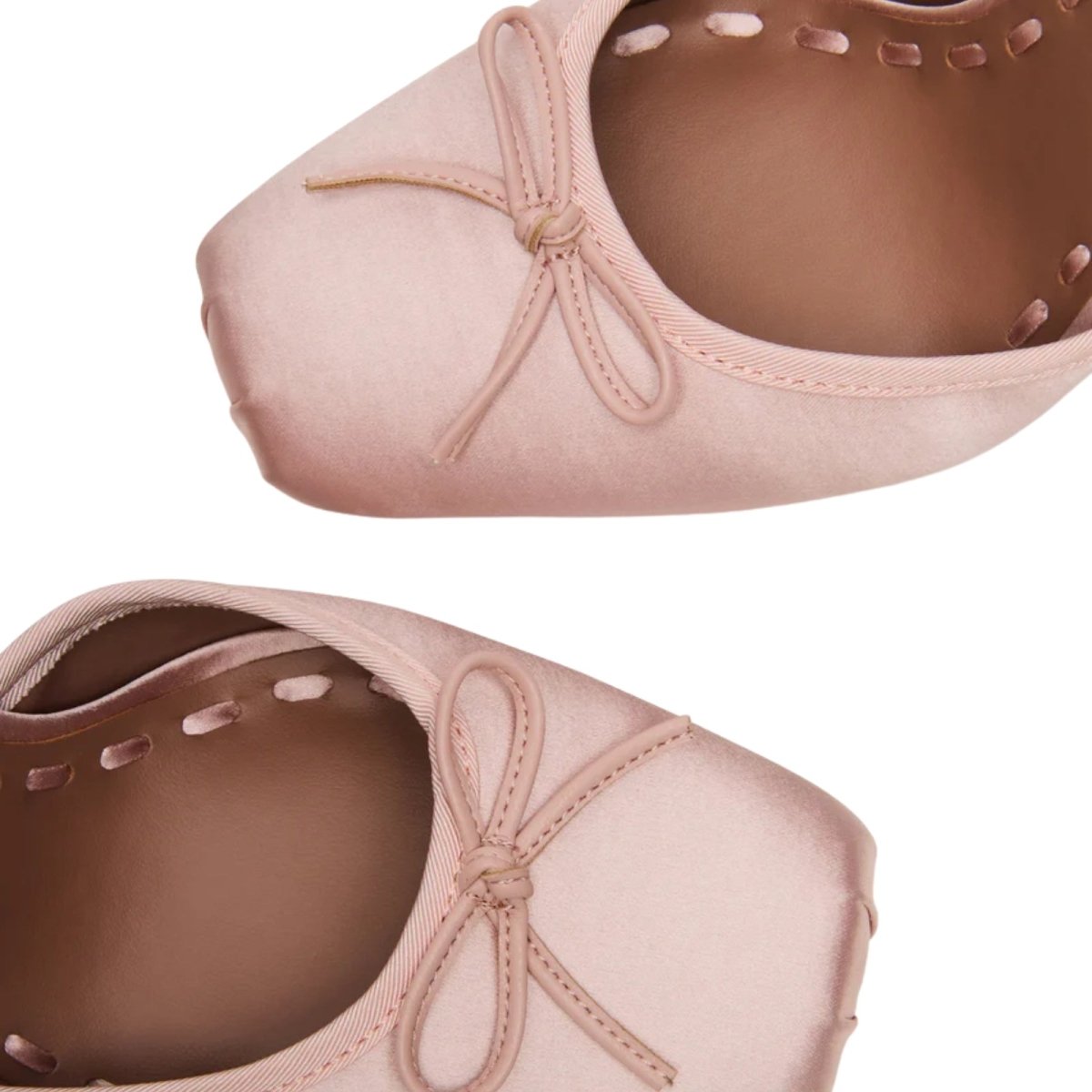 Pair of pink kouvr ballet shoes with a bow on a white background