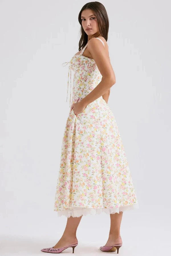 Model wearing Kouvr Fashion Aviva floral corset midi dress in white with pink and yellow flowers, showing the lace-up bustier and A-line skirt