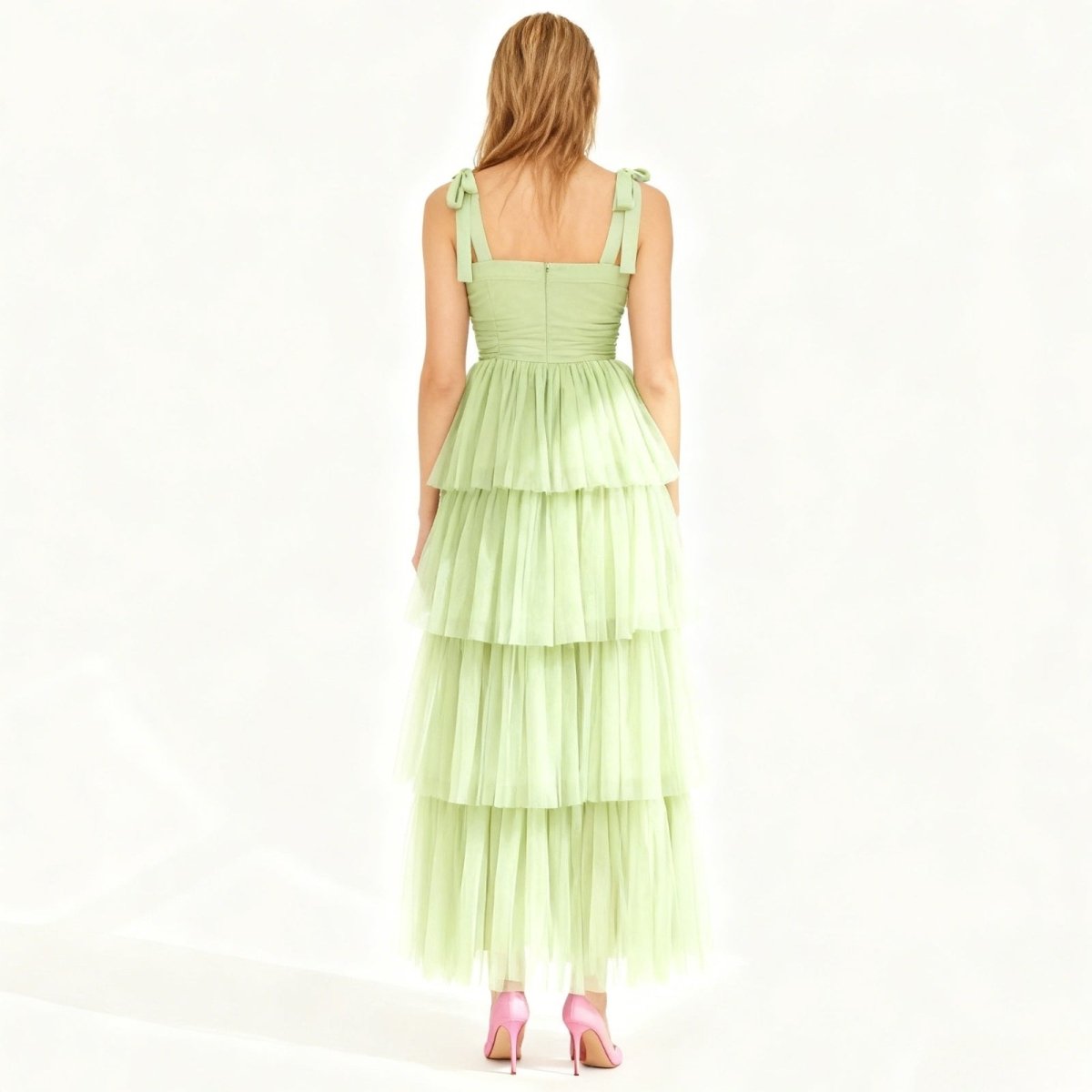 Woman wearing a light green Kouvr tiered dress on a white background