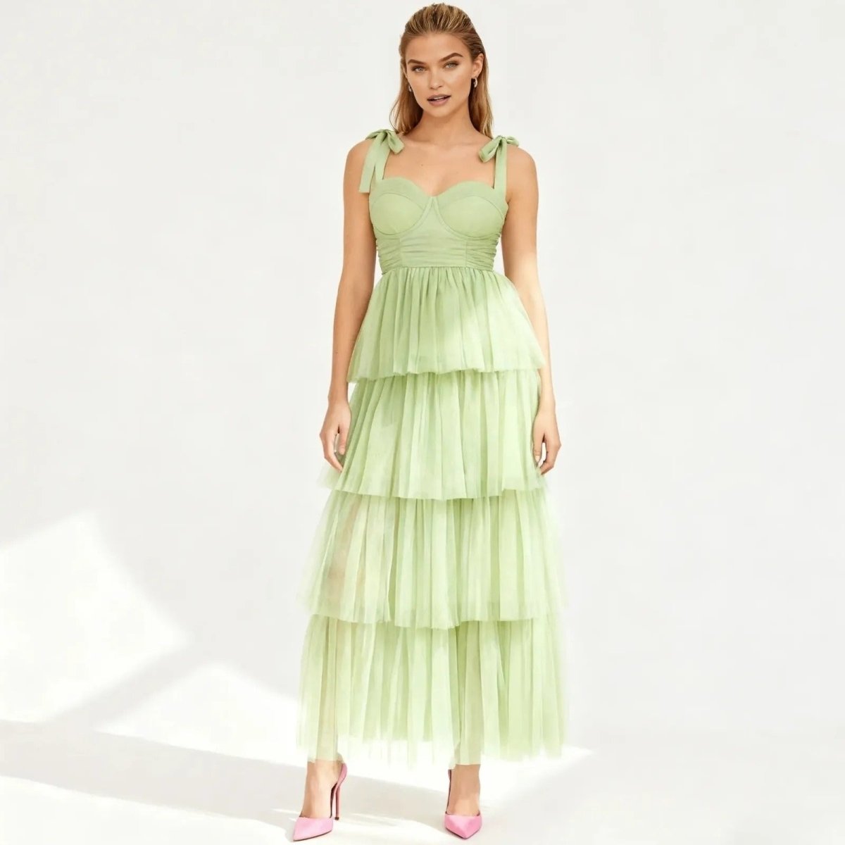 Woman wearing a light green Kouvr tiered dress on a white background