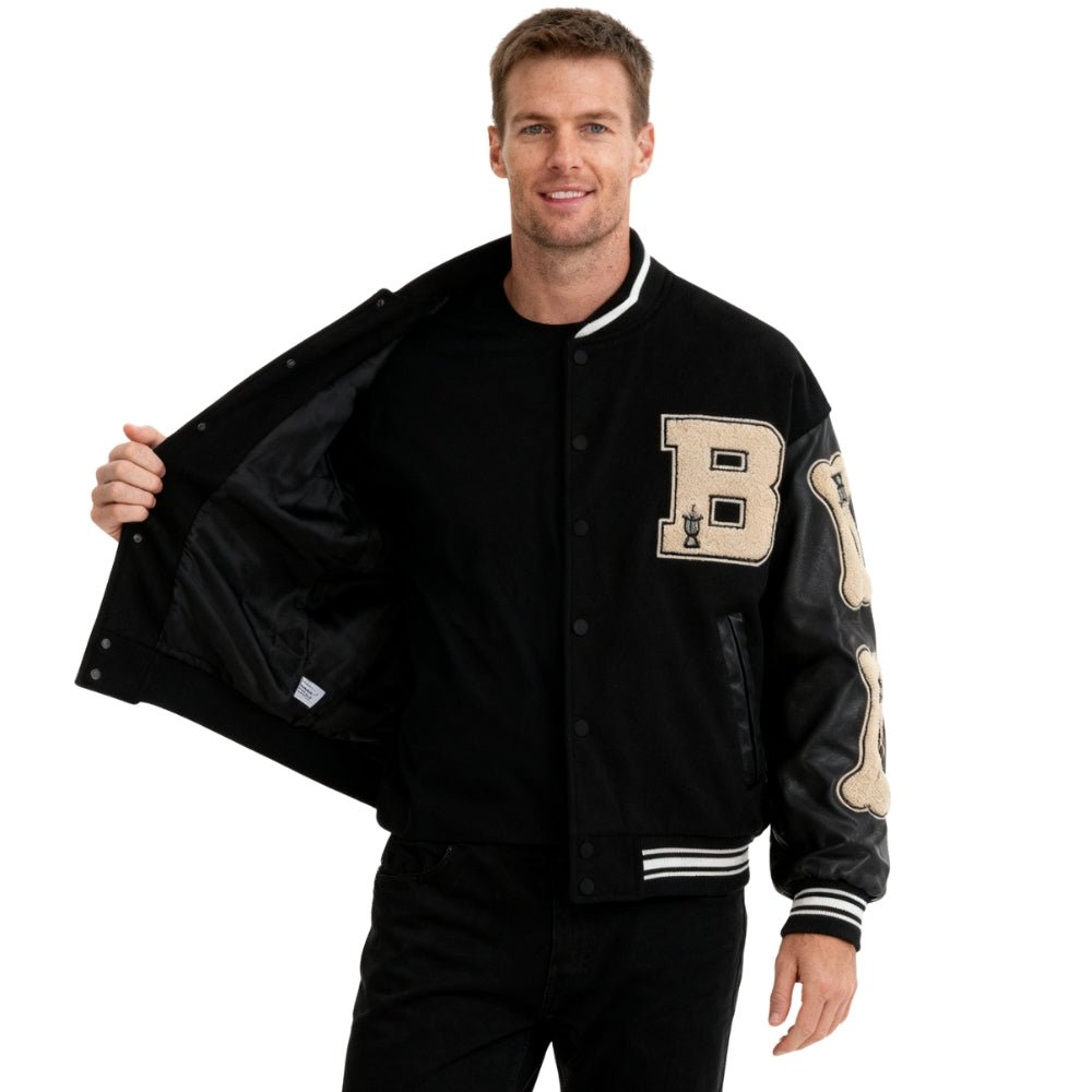 Man wearing a black Kouvr varsity jacket with a letter 'B' on a white background