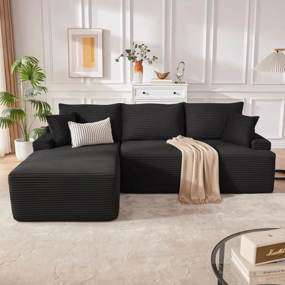 Kouvr modular deep seat sofa in black and dark grey corduroy shown in an L-shape with a beige throw blanket