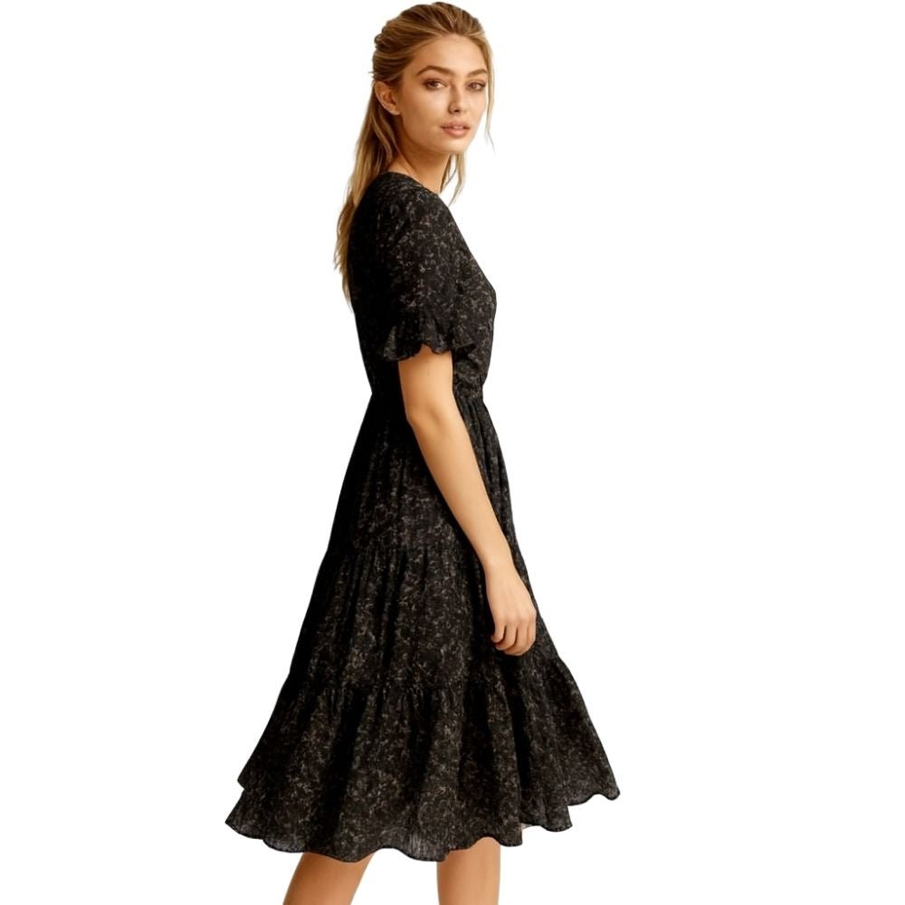 Woman wearing a kouvr  black floral dress on a white background