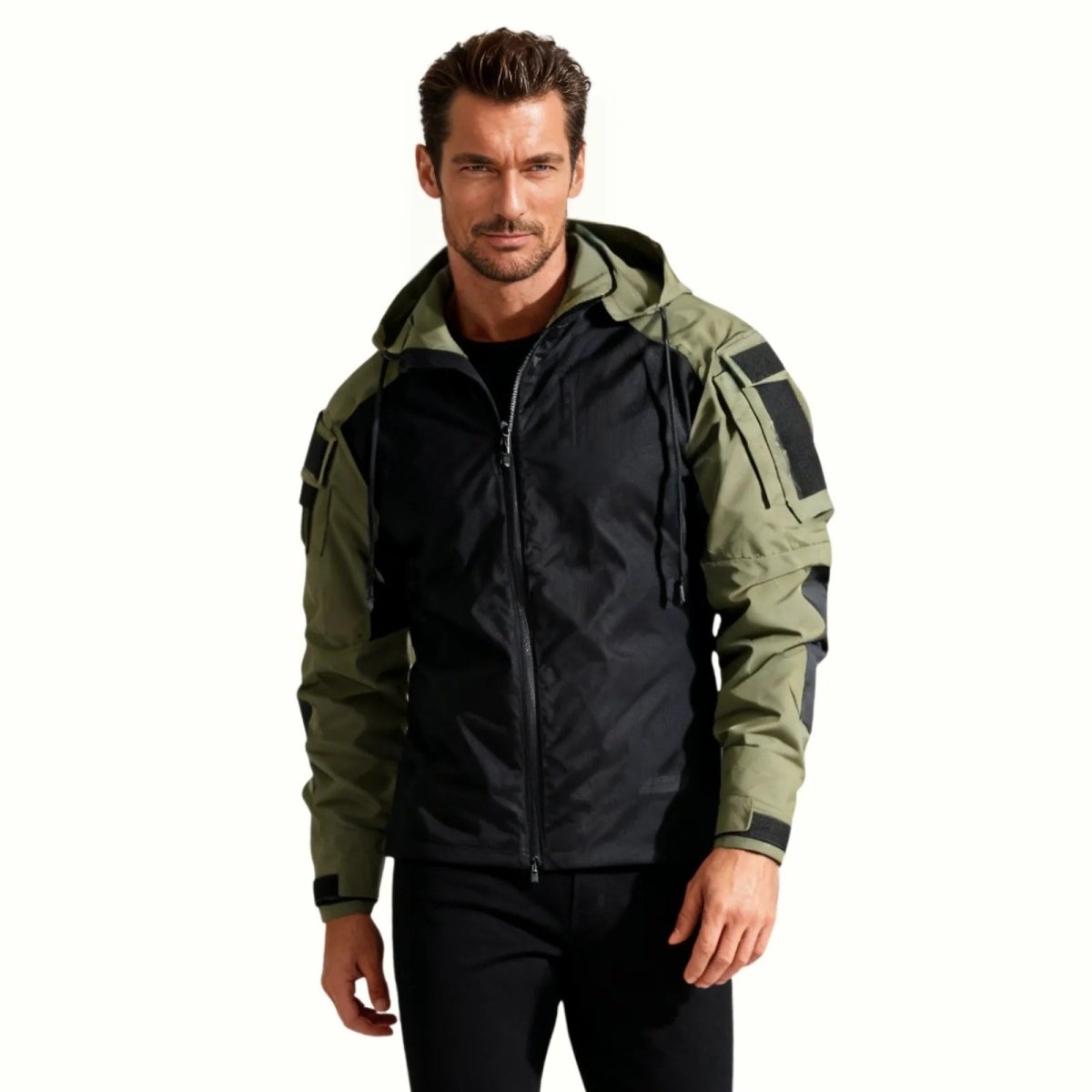 Man wearing the Kouvr Fashion Clint tactical softshell jacket in dark green and black, showing the hooded front view and modern fit.