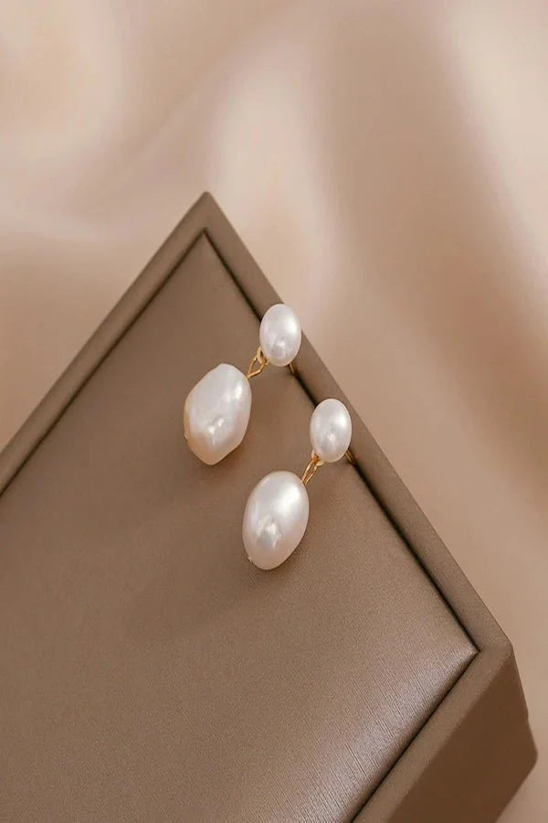 Pearl Kouvr earrings on a brown jewelry box with a soft beige background