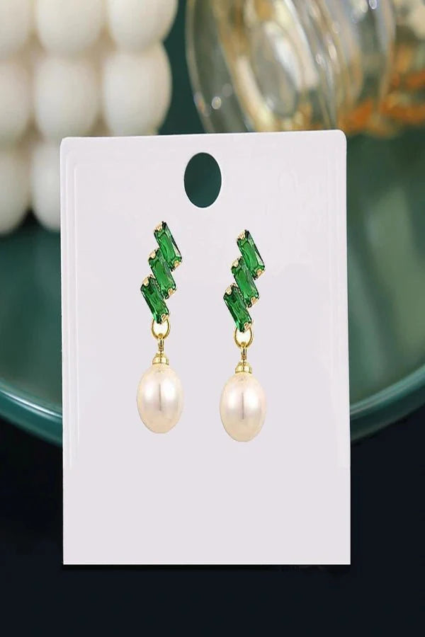 Pair of Kouvr earrings with green gemstones and pearl drops on a white card.