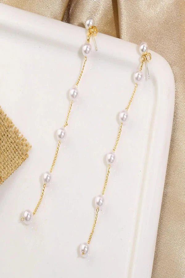 Pearl Kouvr Earring with gold chain on a white and beige fabric background