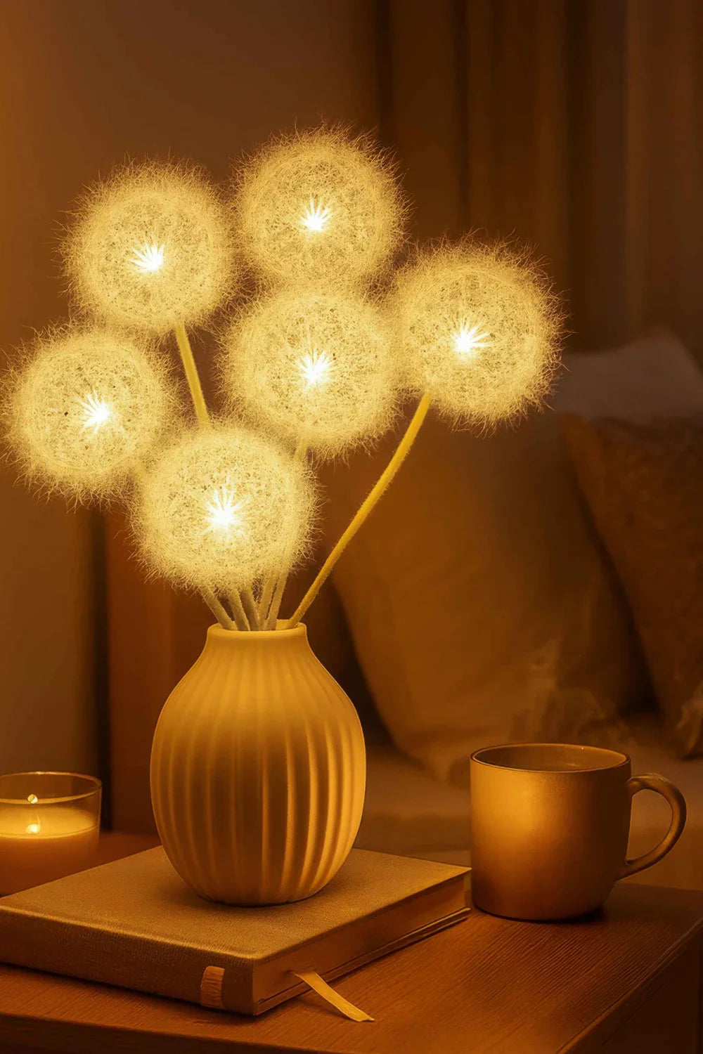 Close-up of the Kouvr Floral Accent Lamp, showing the detailed, glowing dandelion heads in a white ceramic vase on a dining table.
