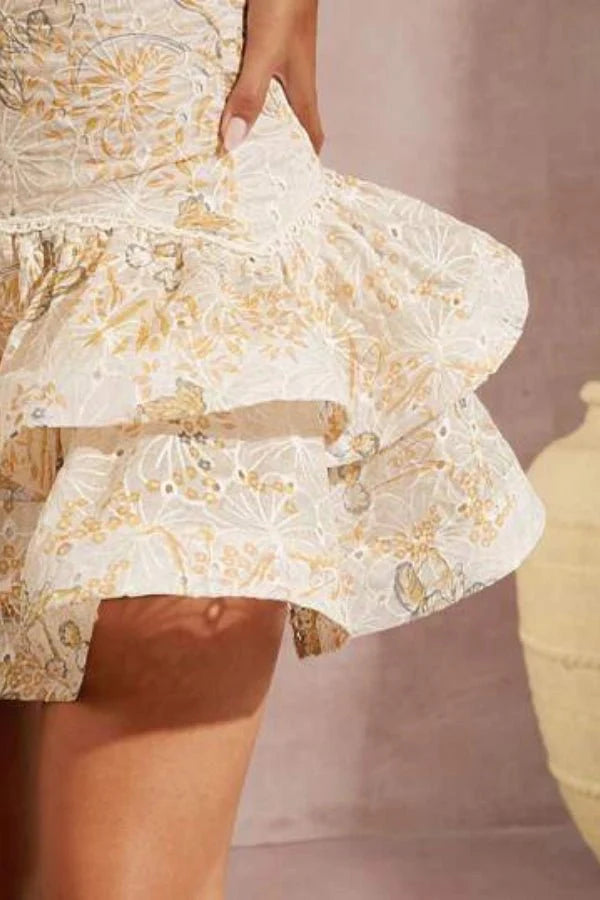 Model wearing Kouvr Fashion Faye beige embroidered halter mini dress with tiered ruffles