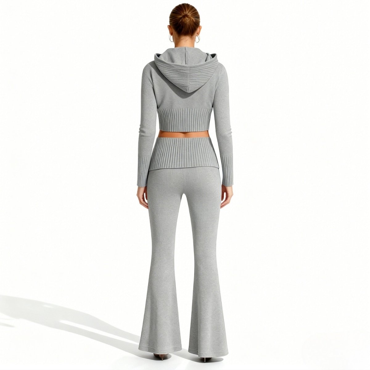The back view of a model wearing the grey knit tracksuit by Kouvr Fashion, highlighting the ribbed detail on the hood and waistband.