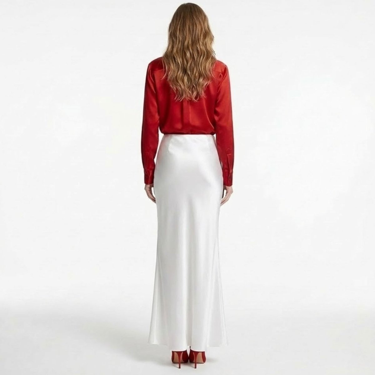 Back view of a woman in a high-waisted white silk maxi skirt from Kouvr Fashion, showcasing its clean lines and luxurious sheen.
