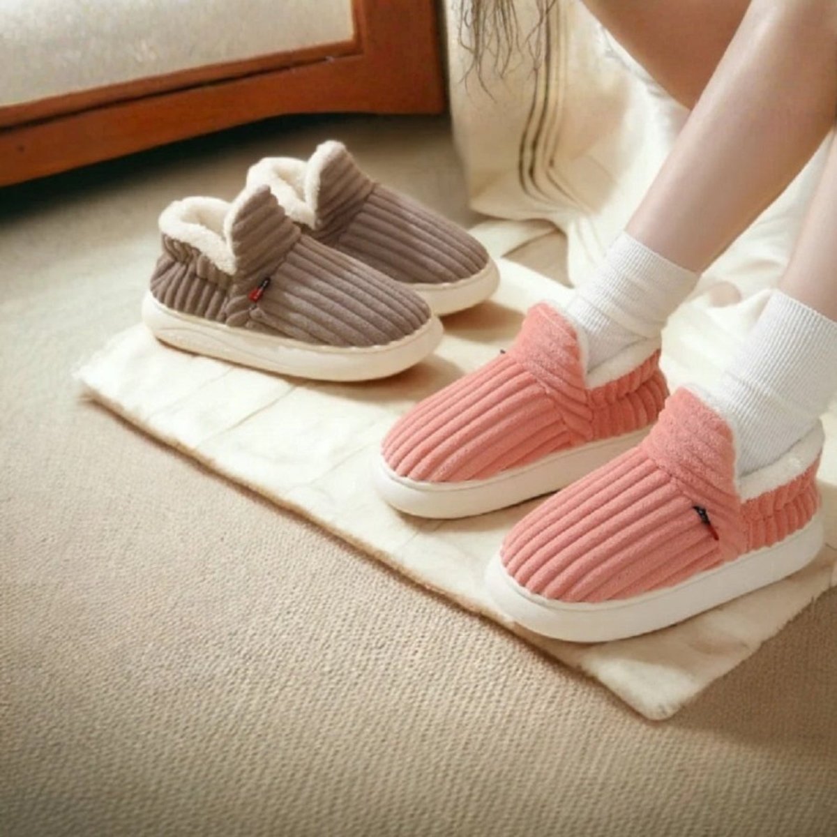 A woman wearing Kouvr Fashion's pink Jasmine corduroy slipper boots with plush white sherpa lining, sitting in a cozy, sunlit room.
