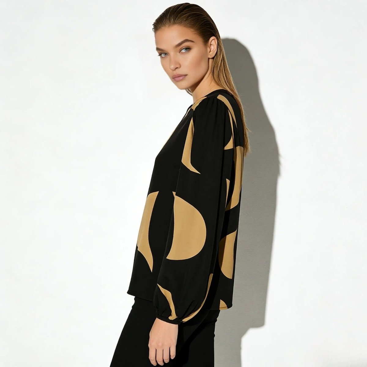 Side view of a model in the Judith abstract print blouse showcasing the voluminous bishop sleeve and fluid drape of the fabric. 