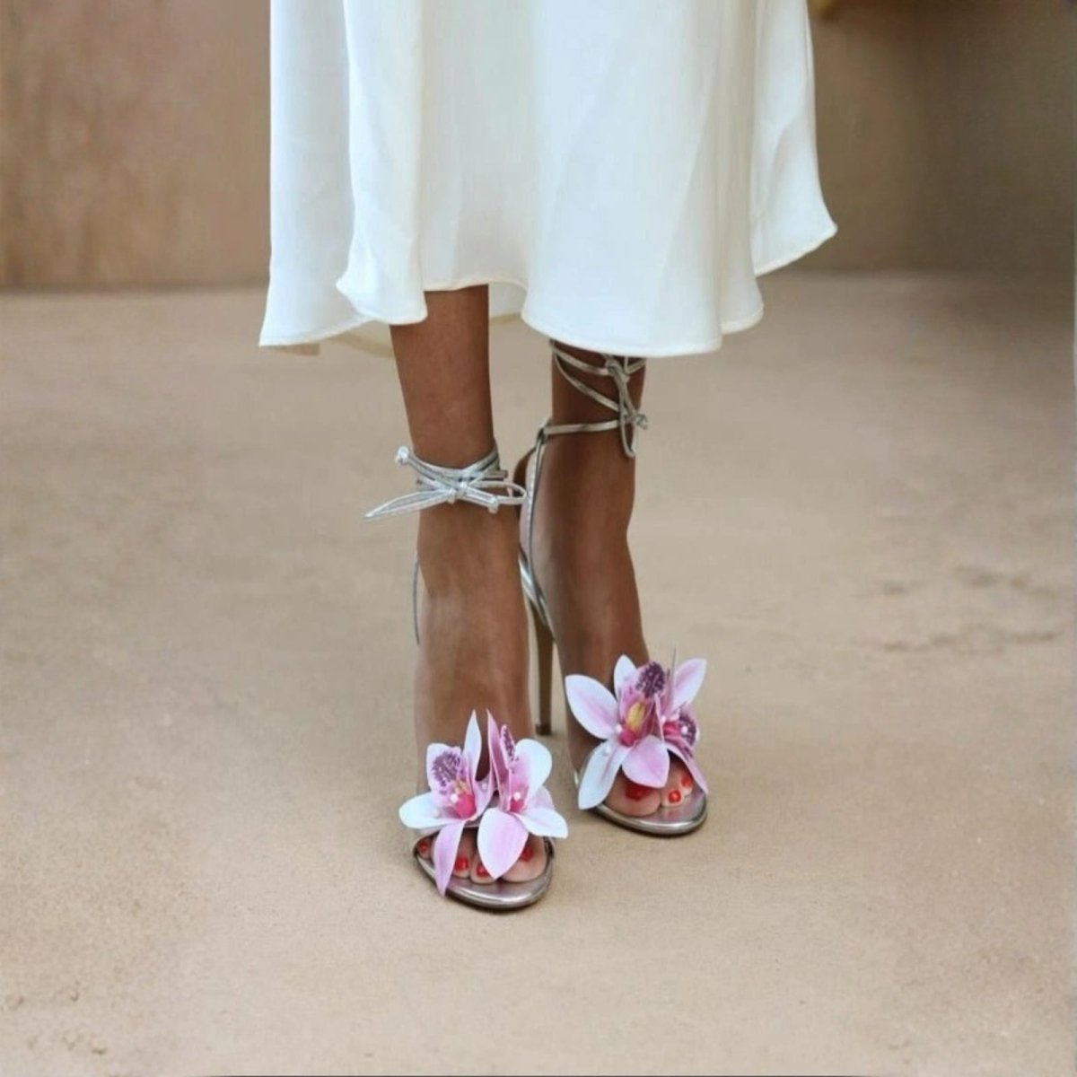 Woman wearing a high-heeled sandals with floral details on a rooftop at sunset.