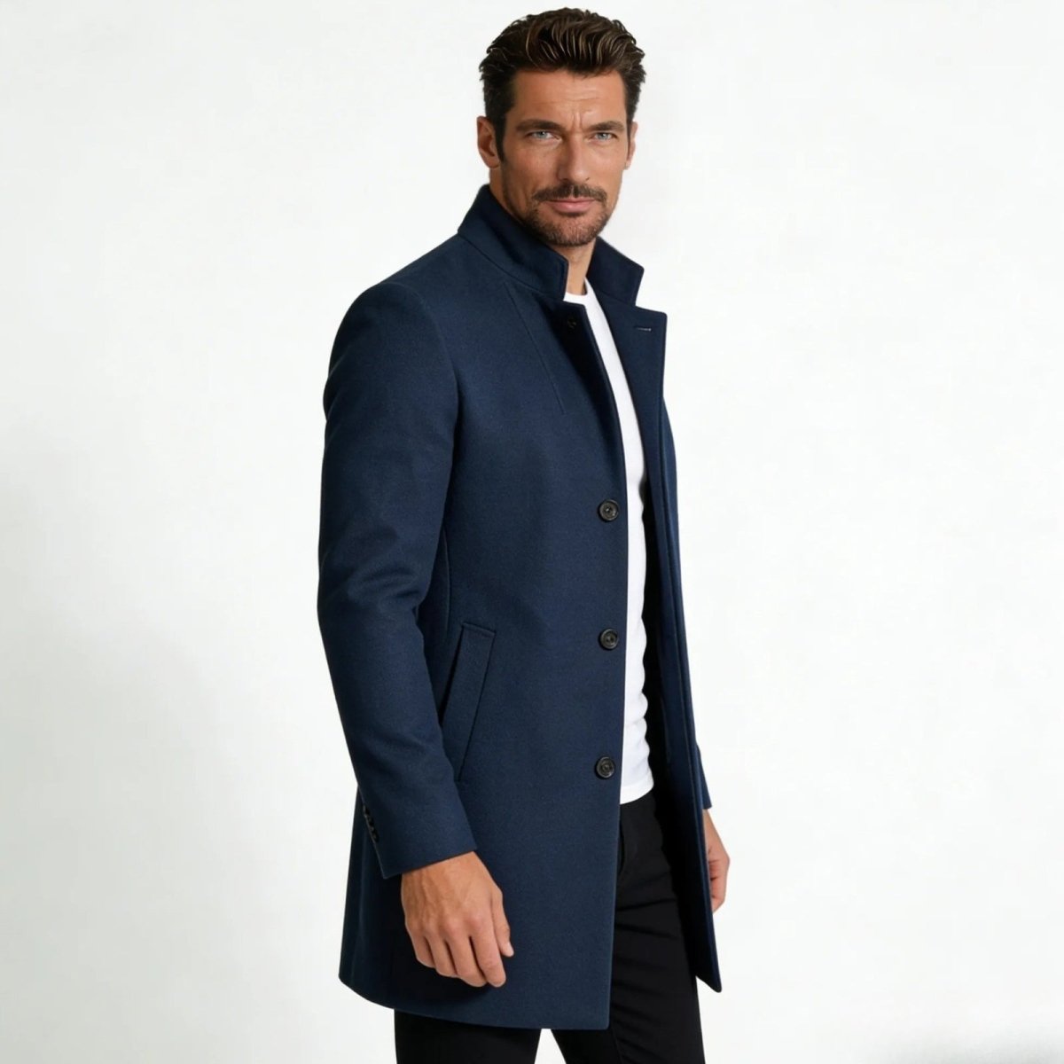 Side profile view of a man in a slim-fit blue wool winter topcoat with a stand-up funnel neck collar.